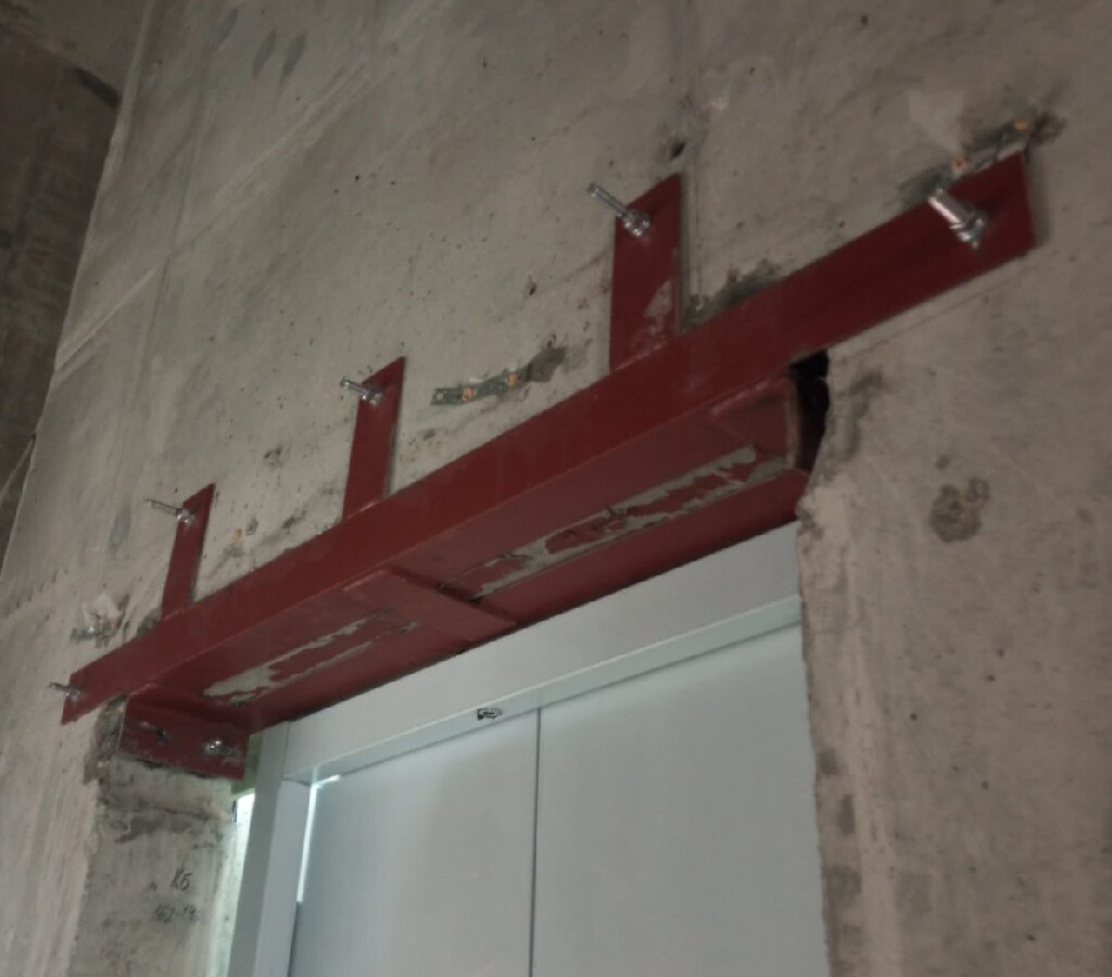 Металлоконструкция на анкерах прочно соединяет бетонную стену с верхней частью дверного проёма.